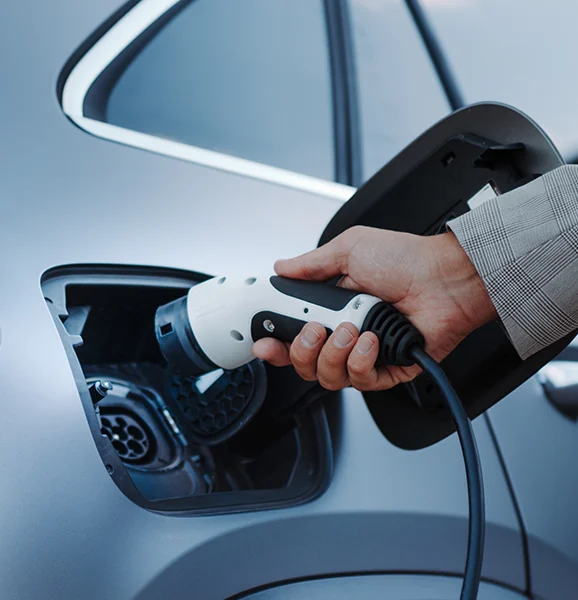 Mann steckt einen Ladestecker in ein E-Fahrzeug